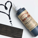 Dixie Belle's Black Magic Voodoo Gel Stain is against a white background with a wood stained swatch and a poured color sample.