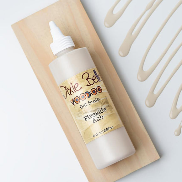 Dixie Belle's Fireside Ash Voodoo Gel Stain is against a white background with a wood stained swatch and a poured color sample.