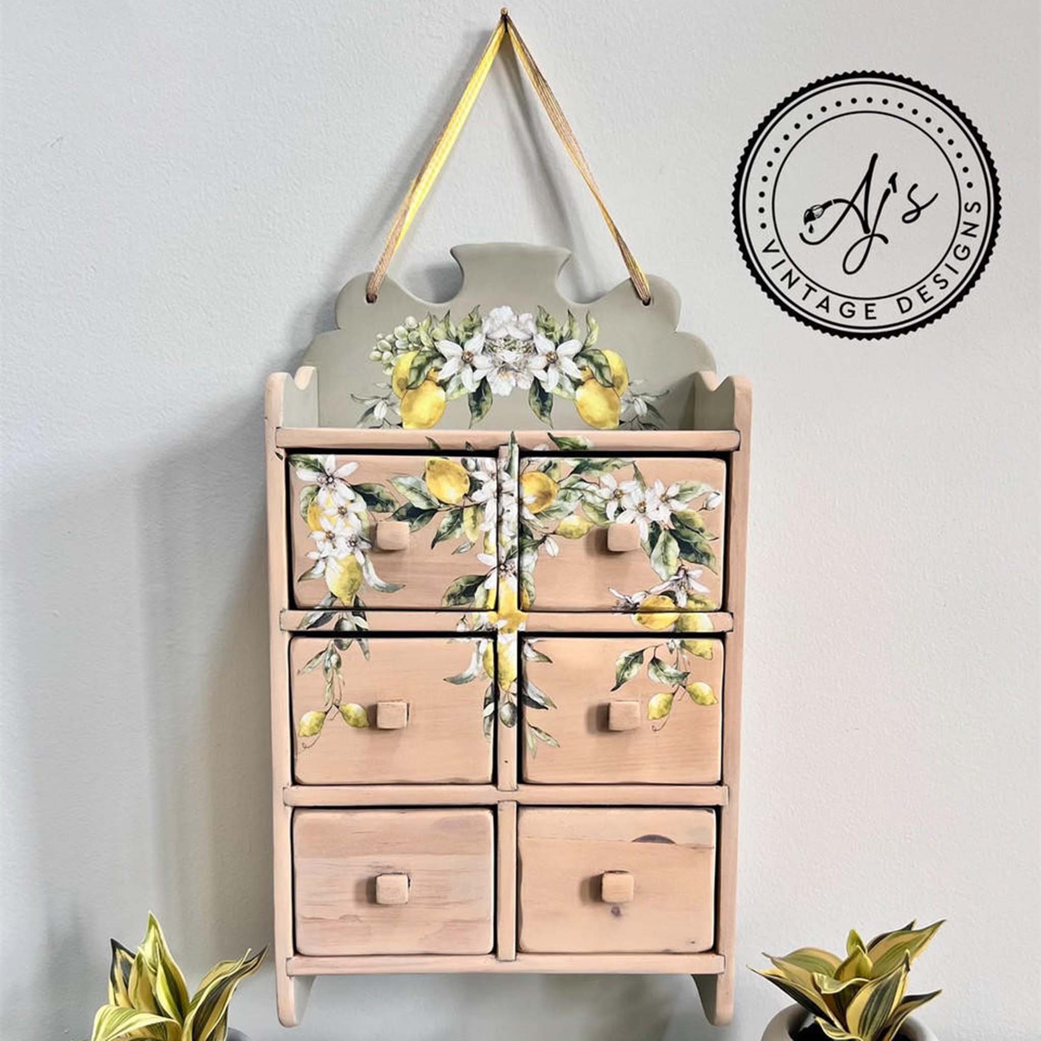 A small hanging card catalog shelf refurbished by Aj's Vintage Designs is painted light coral pink and features Belles & Whistles' Lemon Zest small transfer on it.