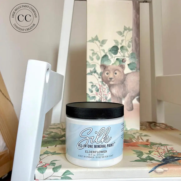 Jar of Silk mineral paint on a surface with a decorative item in the background