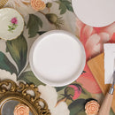 White round object on a decorative table with floral patterns and a gold frame.