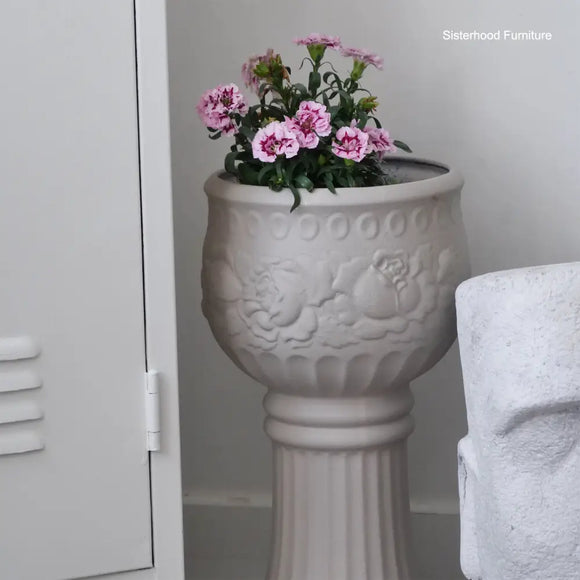 Decorative urn with pink flowers against a neutral background