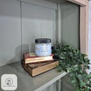 Candle on top of books with a plant nearby on a shelf