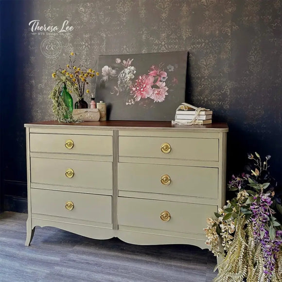 Vintage-style dresser with gold knobs against a floral-patterned wall.