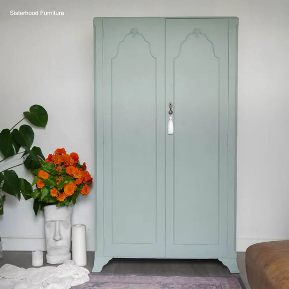 Light green wardrobe with decorative elements in a room setting.