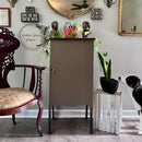 Room interior with a wooden chair, cabinet, and decorative items on a wall.