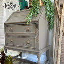 Gray wooden desk with decorative elements and greenery, featuring 'Tracey's Fancy' branding.