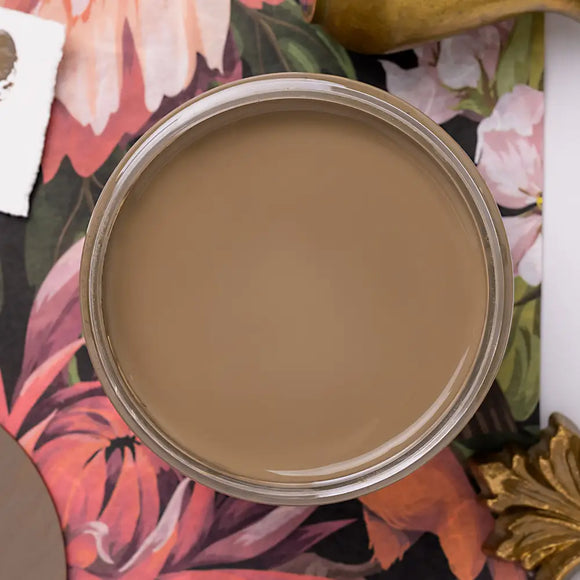Close-up of a brown paint jar on a floral fabric background