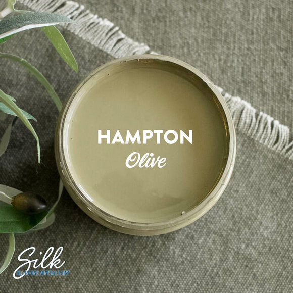 An arial view of an open container of Dixie Belle Paint Company's Hampton Olive Silk All-In-One Mineral Paint is shown with white text reading Hampton Olive.