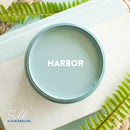 An arial view of an open container of Dixie Belle Paint Company's Harbor Silk All-In-One Mineral Paint is shown with white text reading Harbor.