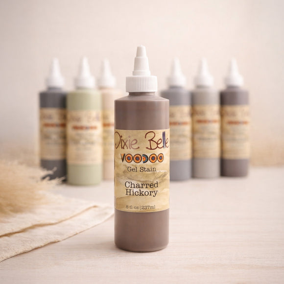 Dixie Belle Voodoo Gel Stain Charred Hickory bottle centered with other stain colors softly blurred in the background, styled in warm neutral light.