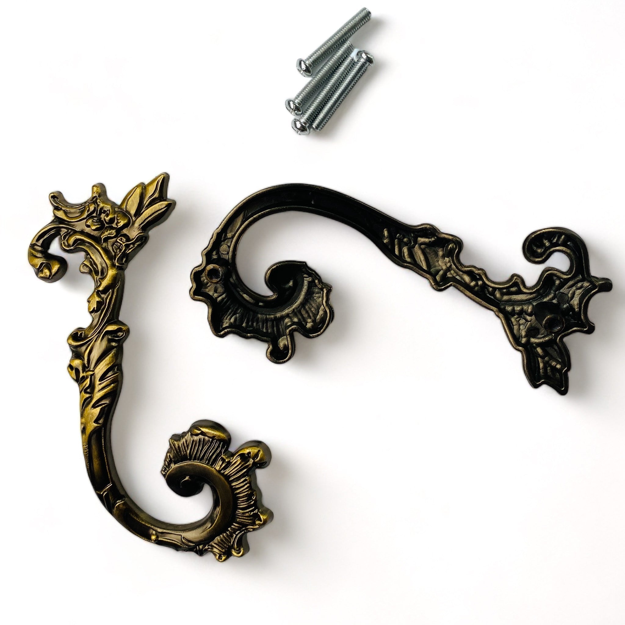 Two metal drawer pulls and 4 screws featuring swirling flourished and floral details are against a white background.