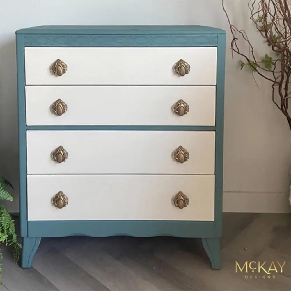 A 4-drawer chest dresser refurbished by McKay Designs is painted in Dixie Belle's Blue Grass Chalk Mineral Paint with Dixie Belle's Ecru Chalk Mineral Paint on the drawers.