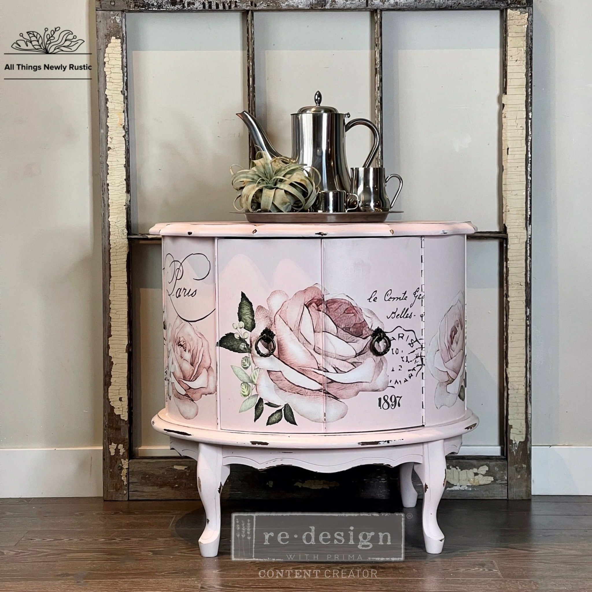 A vintage round drum table refurbished by All Things Newly Rustic, a ReDesign with Prima Content Creator, is painted pale pink and features the Chatellerault transfer on its doors.