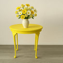 A small round side table features KACHA Lemon Yellow furniture paint and has a small vase with a bouquet of white and yellow flowers on it.