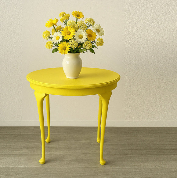 A small round side table features KACHA Lemon Yellow furniture paint and has a small vase with a bouquet of white and yellow flowers on it.