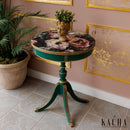 A vintage round side table refurbished by Kacha features Kacha Maine Forest Green paint with gold trim and a pink floral design on the table top.