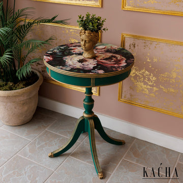 A vintage round side table refurbished by Kacha features Kacha Maine Forest Green paint with gold trim and a pink floral design on the table top.