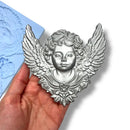 Decorative angel figurine held in a hand with a blue textured background