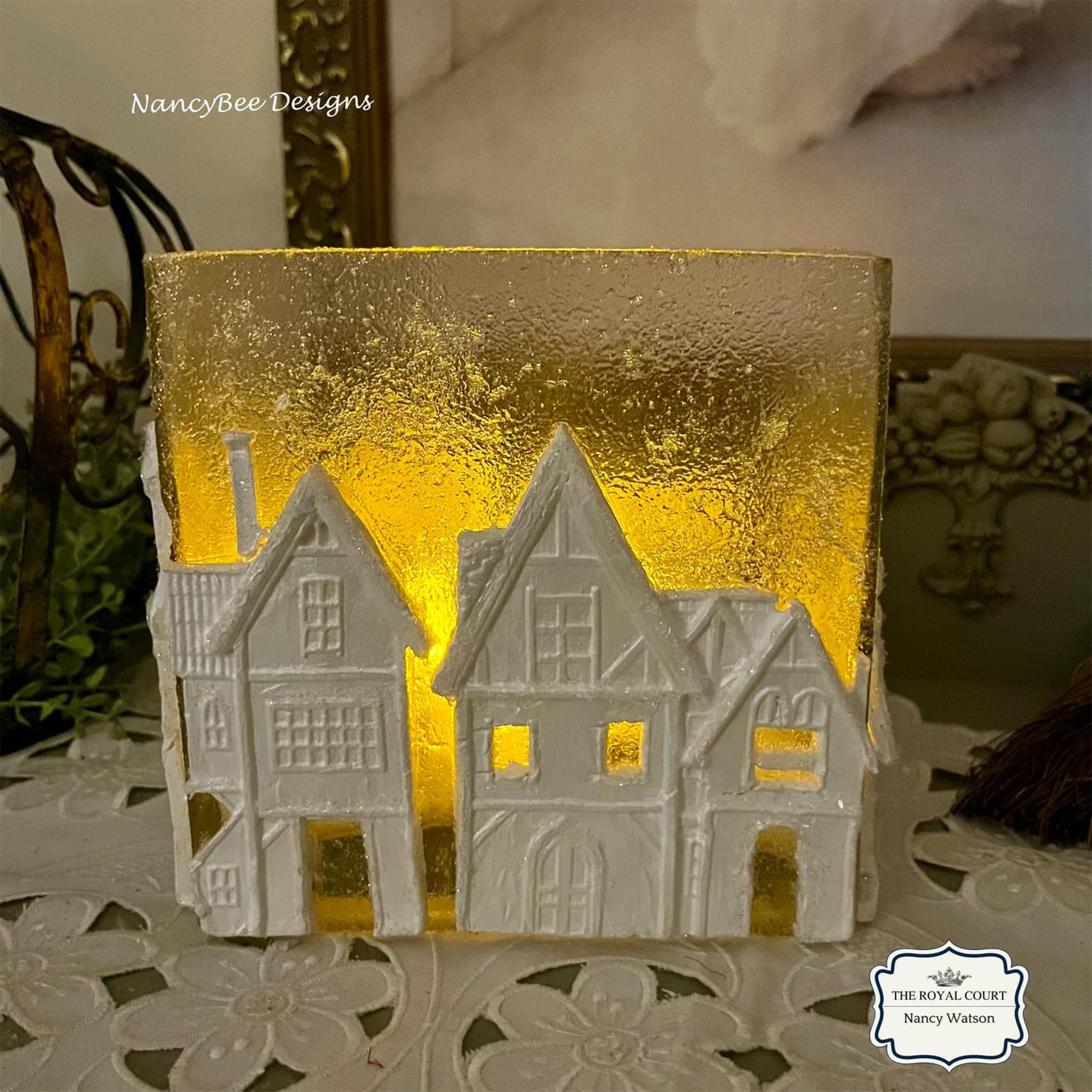 White painted silicone mold castings created by Nancy Bee Designs are made from LaBlanche's Houses 1 and have a frosted backlit piece of glass behind them.