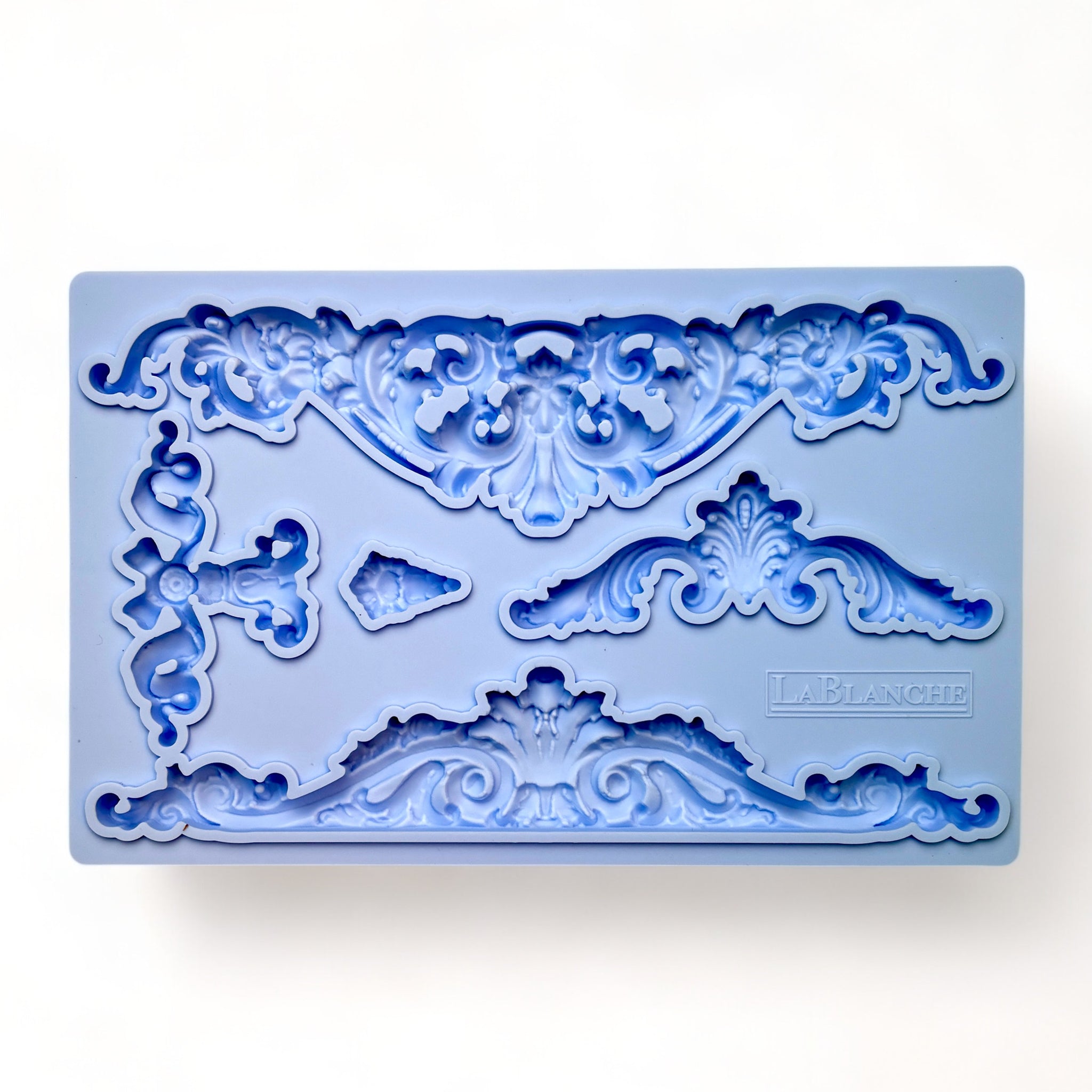 A blue silicone mold of 5 ornate scroll center accent pieces is against a white background.