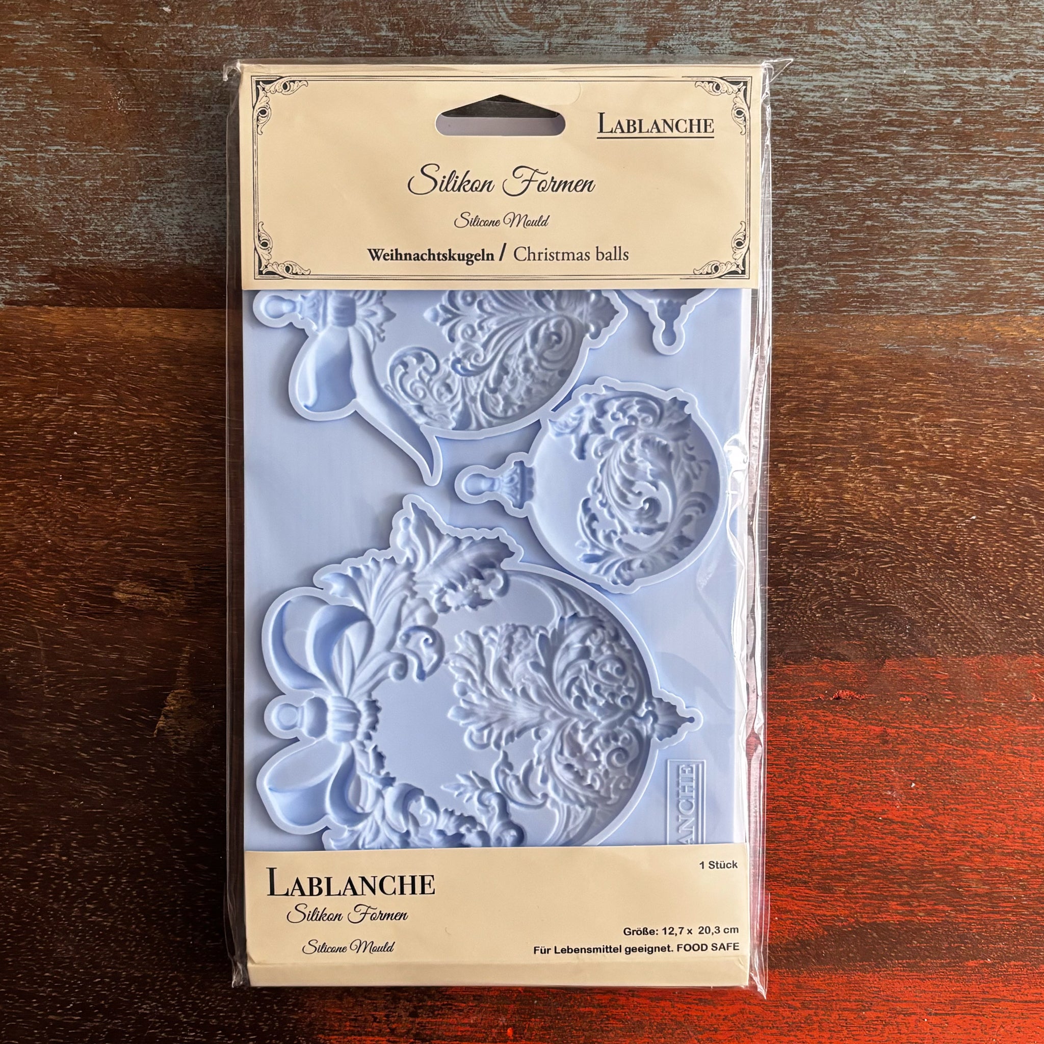 A package of LaBlanche's Christmas Balls silicone mold is against a dark wood background.