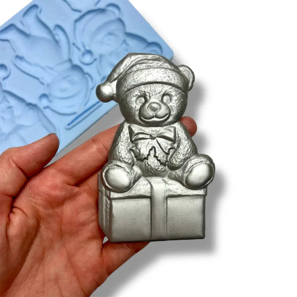 Silver painted bear mold held in a hand on a white background