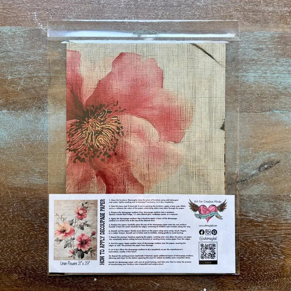 A package of Whimsykel's Linen Flowers tissue paper is against a wood background.