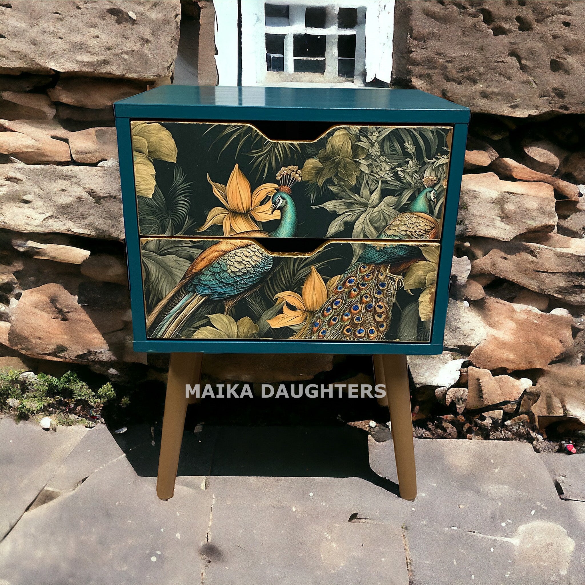 A modern mid century 2-drawer nightstand is painted teal and features Mint by Michelle's A Peacock Pair decoupage paper on the drawers.