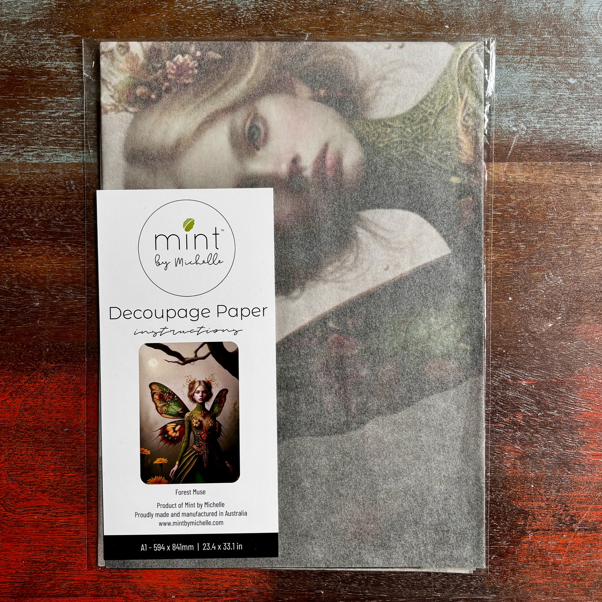 A package of Mint by Michelle’s Forest Muse A1 Decoupage Paper is against a dark wood background. 
