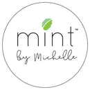A white background has a simple black outlined circle with the words Mint by Michelle with a mint leaf above the letter I in mint.