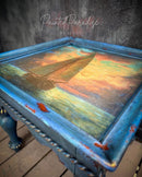 Decorative table with a painted sailboat design on a textured surface