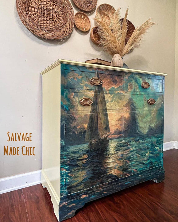 Furniture piece with sailboat design on a wall with decorative items.