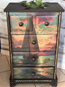 Decorative dresser with sailboat design on drawers against a wooden background