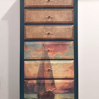A dresser with decorative drawers featuring sailboat designs on a white background