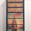 A dresser with decorative drawers featuring sailboat designs on a white background