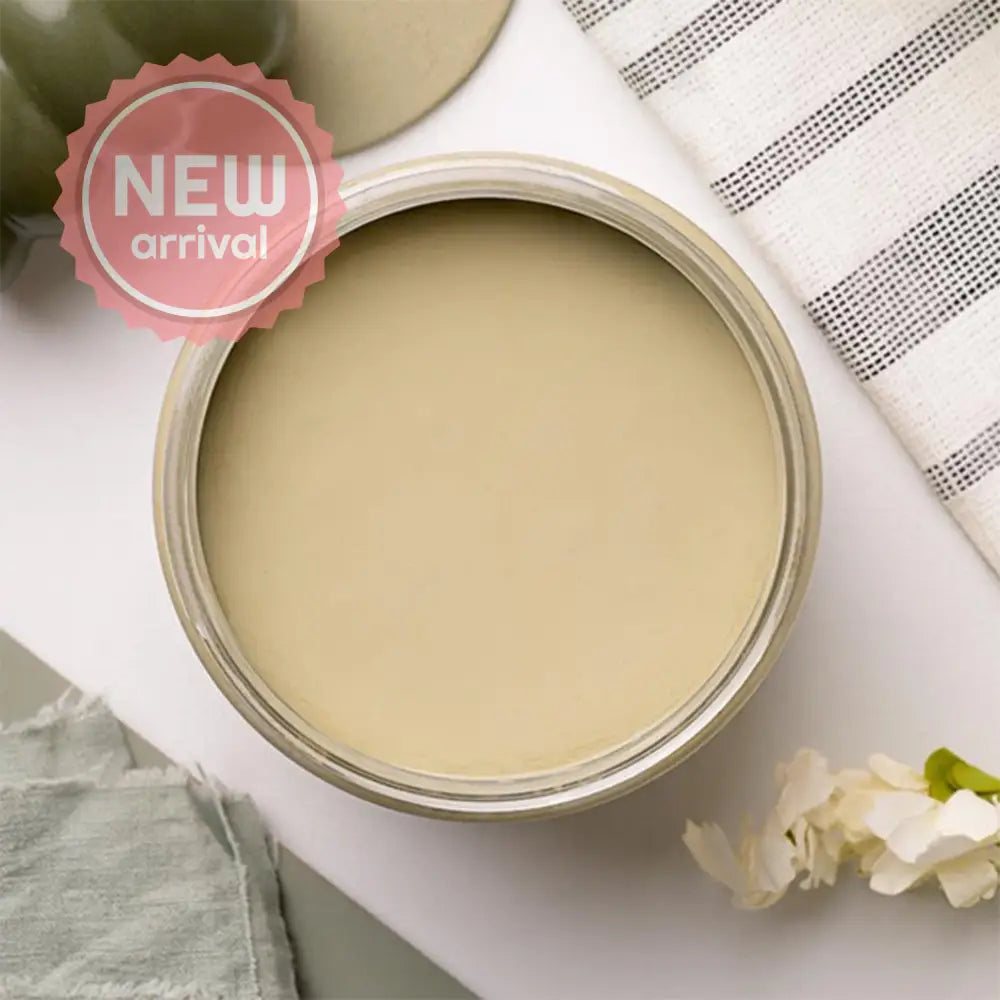 An arial view of an open container of Dixie Belle Paint Company's Olive Wood Chalk Mineral Paint is on a white table with other items.