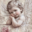 Close-up of 'Rosewood Angel' decoupage paper by Paper Designs Italy, featuring a cherubic child angel with curled hair, resting her head on folded hands. She is surrounded by delicate roses and soft feathered wings in a muted, vintage palette.