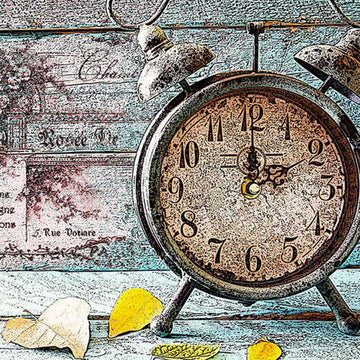 Close-up of a rice paper featuring a faded barnwood design with a vintage metal clock and dried leaves.