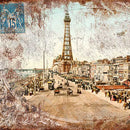 Close-up of a rice paper of a vintage sepia colored postcard featuring a quaint city street with an iron tower in the distance.