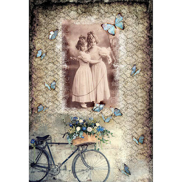 Rice paper featuring a collage of a sepia vintage portrait of two young girls in an embrace against a background of a patterned design with blue butterflies and bicycle with blue flowers in a basket.
