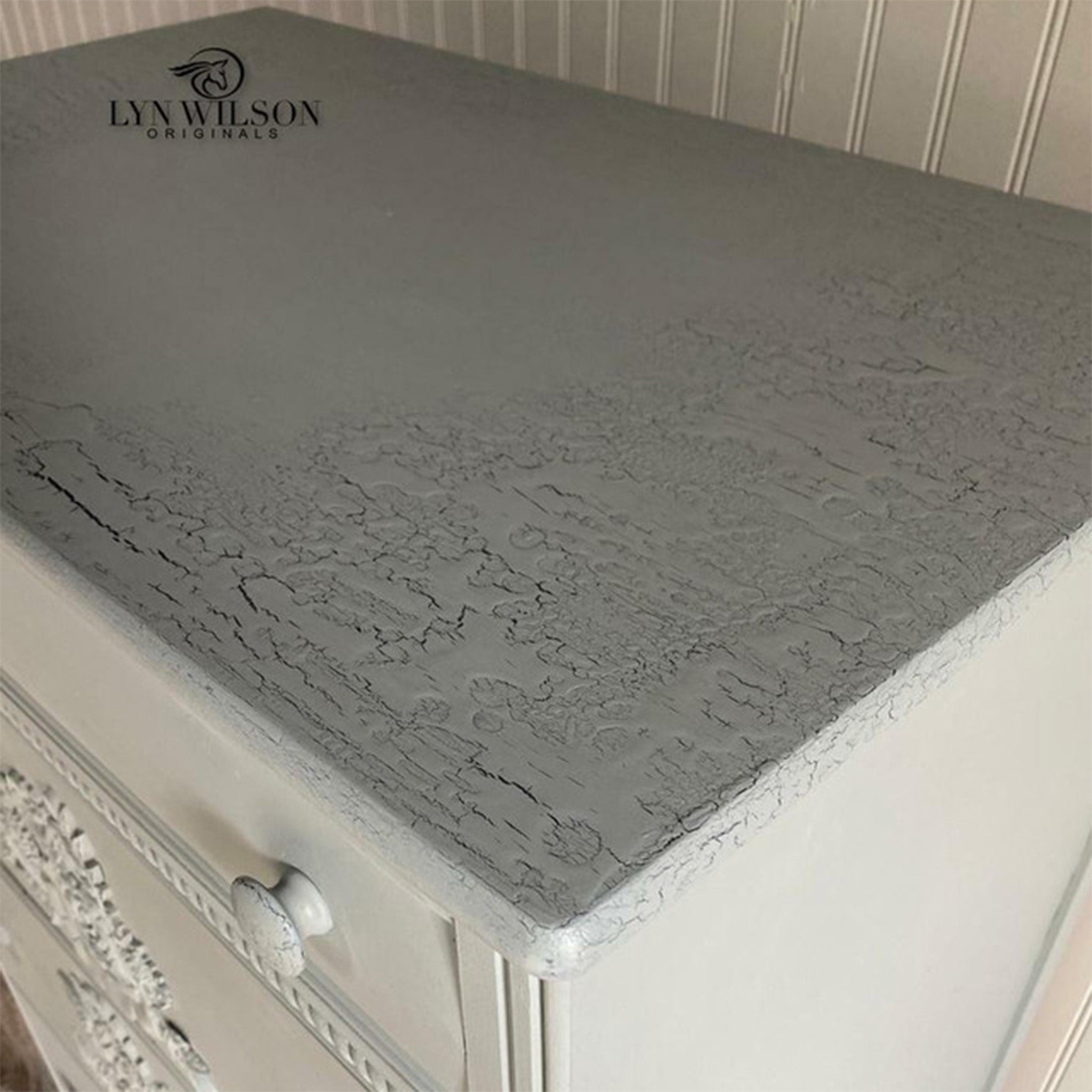 A close-up of a white dresser refurbished by Lyn Wilson Originals features Pentart's Fine Line Crackle on the top and painted grey.