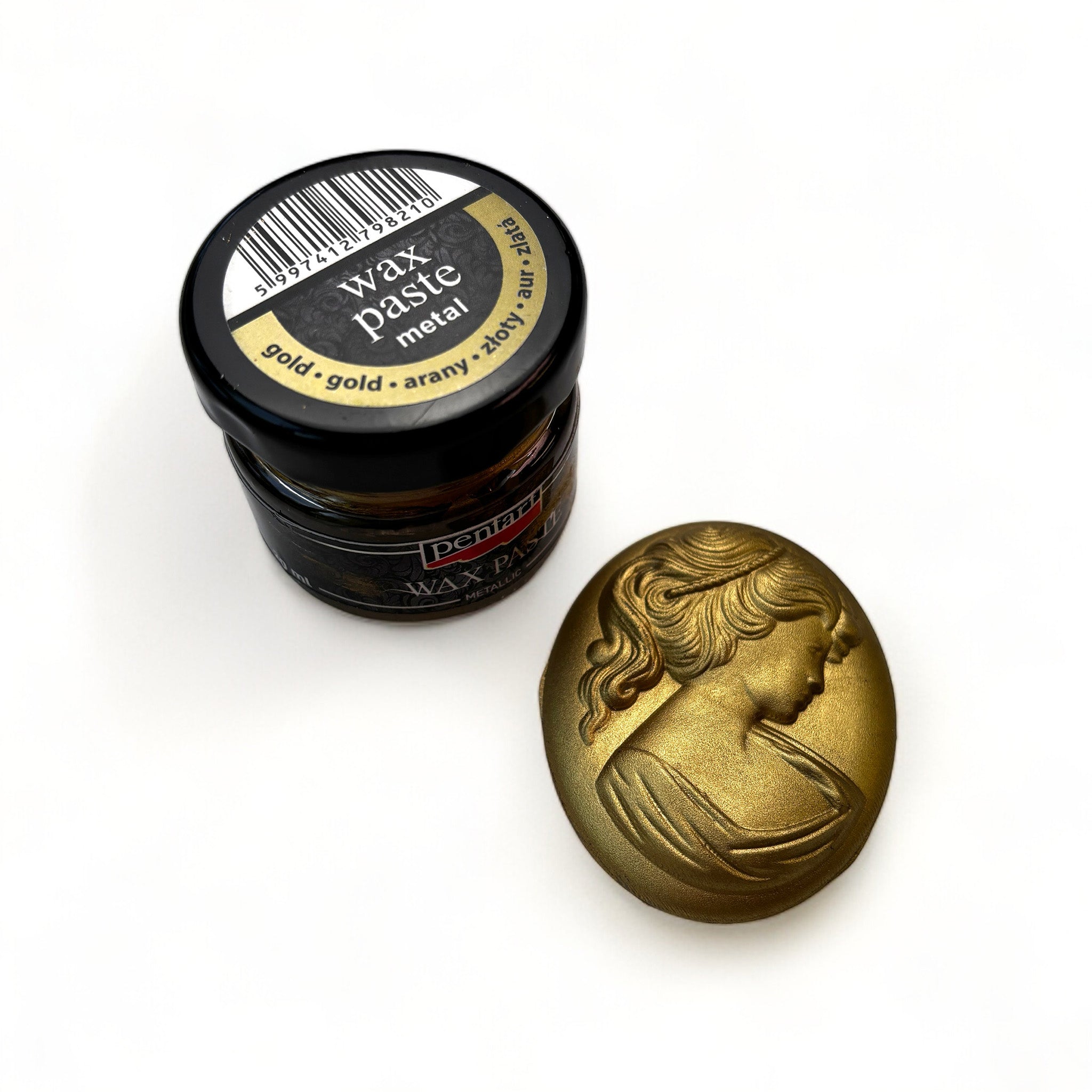 A jar of Pentart's Gold Metallic Wax Paste and a silicone mold casting of a cameo pendant finished in the wax are against a white background.