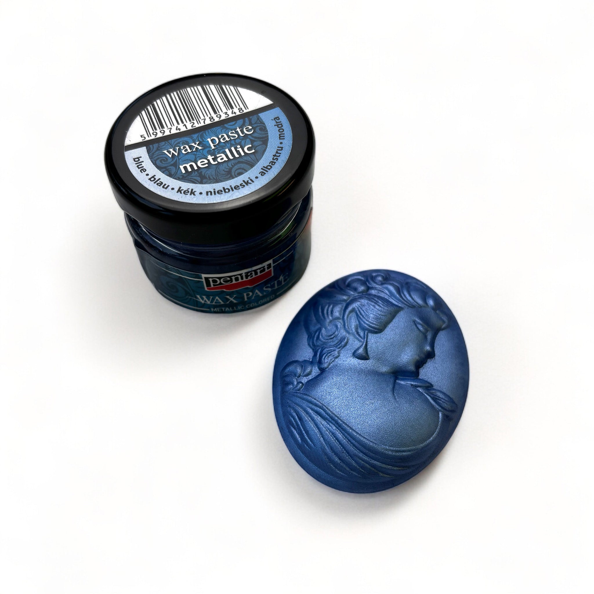 A jar of Pentart's Blue Metallic Wax Paste and a silicone mold casting of a cameo pendant finished in the wax are against a white background.