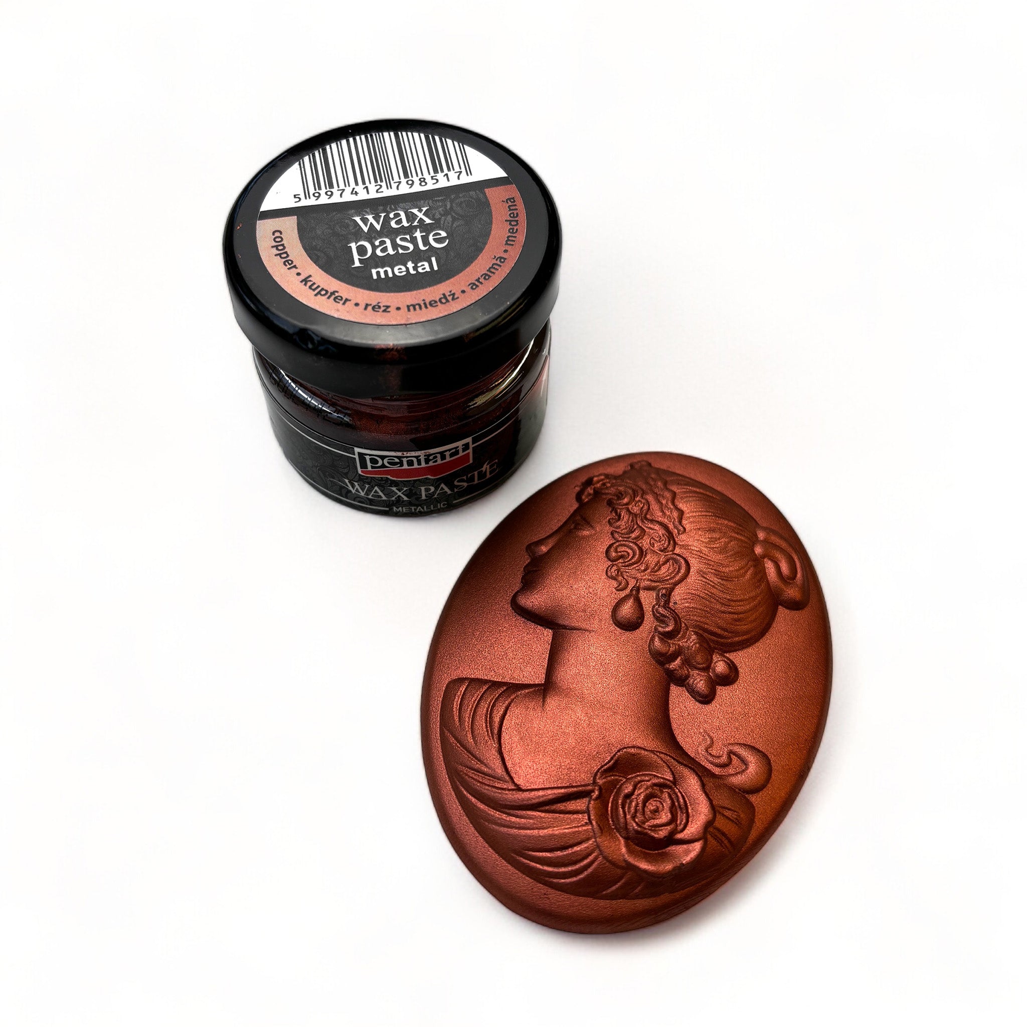 A jar of Pentart's Copper Metallic Wax Paste and a silicone mold casting of a cameo pendant finished in the wax are against a white background.