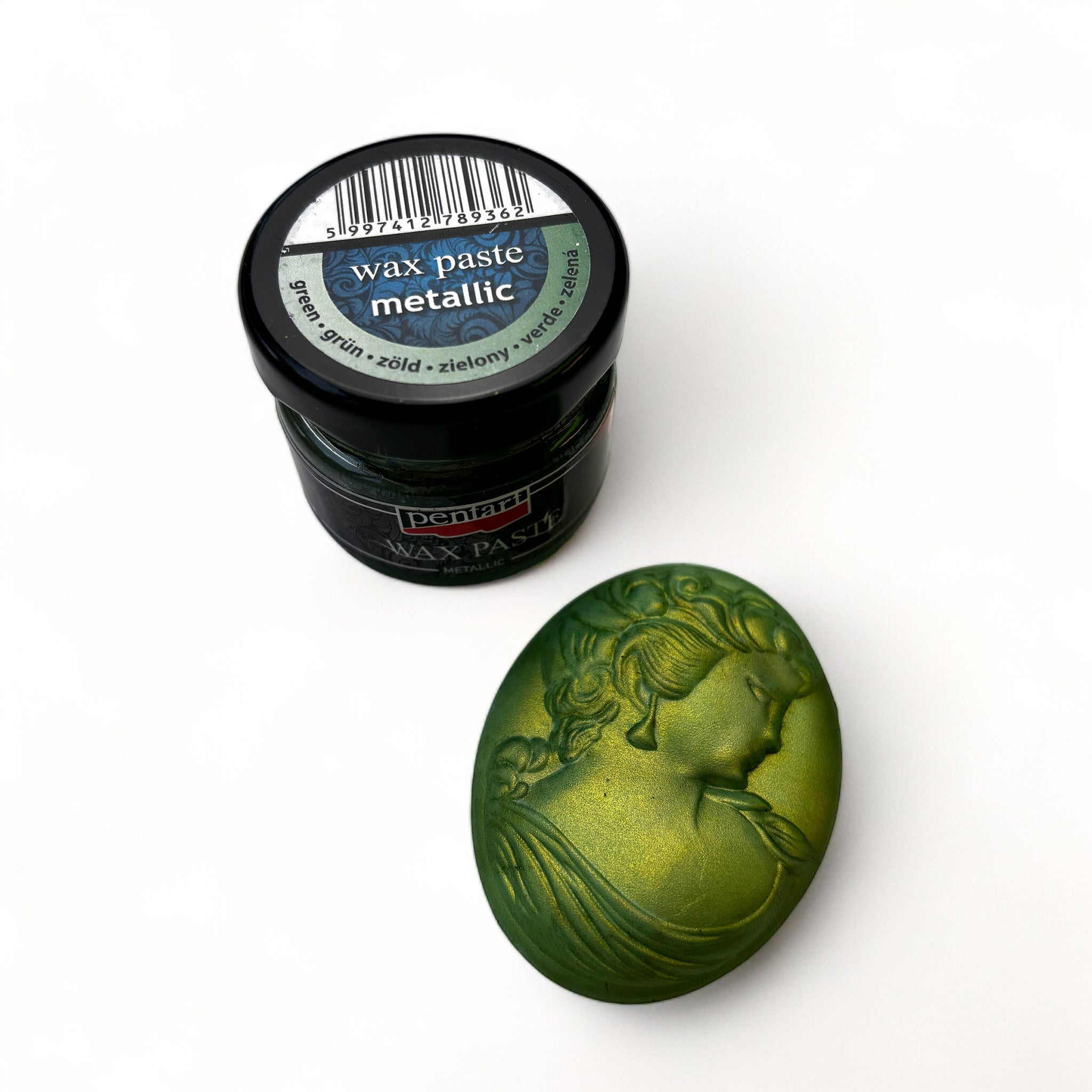 A jar of Pentart's Green Metallic Wax Paste and a silicone mold casting of a cameo pendant finished in the wax are against a white background.