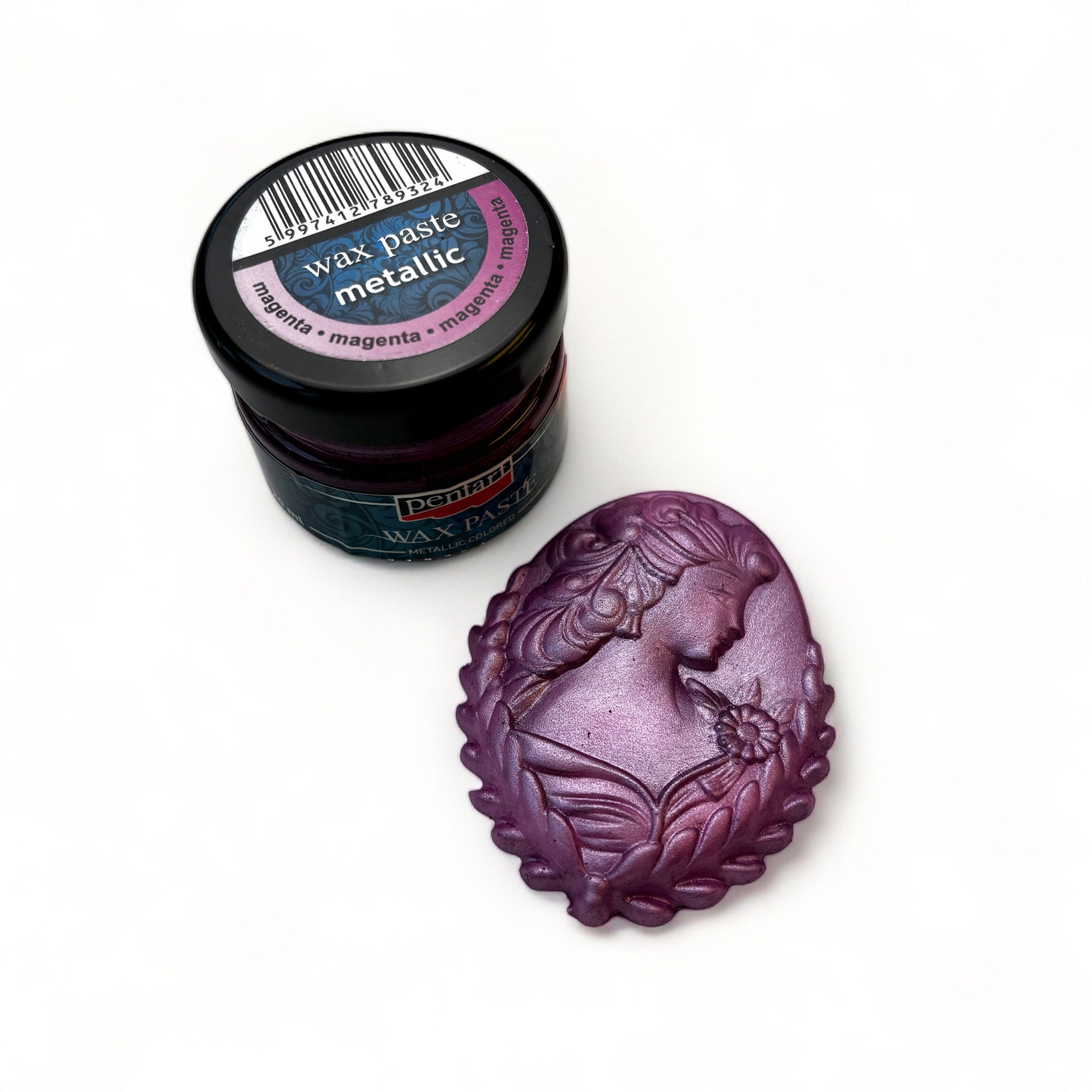 A jar of Pentart's Magenta Metallic Wax Paste and a silicone mold casting of a cameo pendant finished in the wax are against a white background.