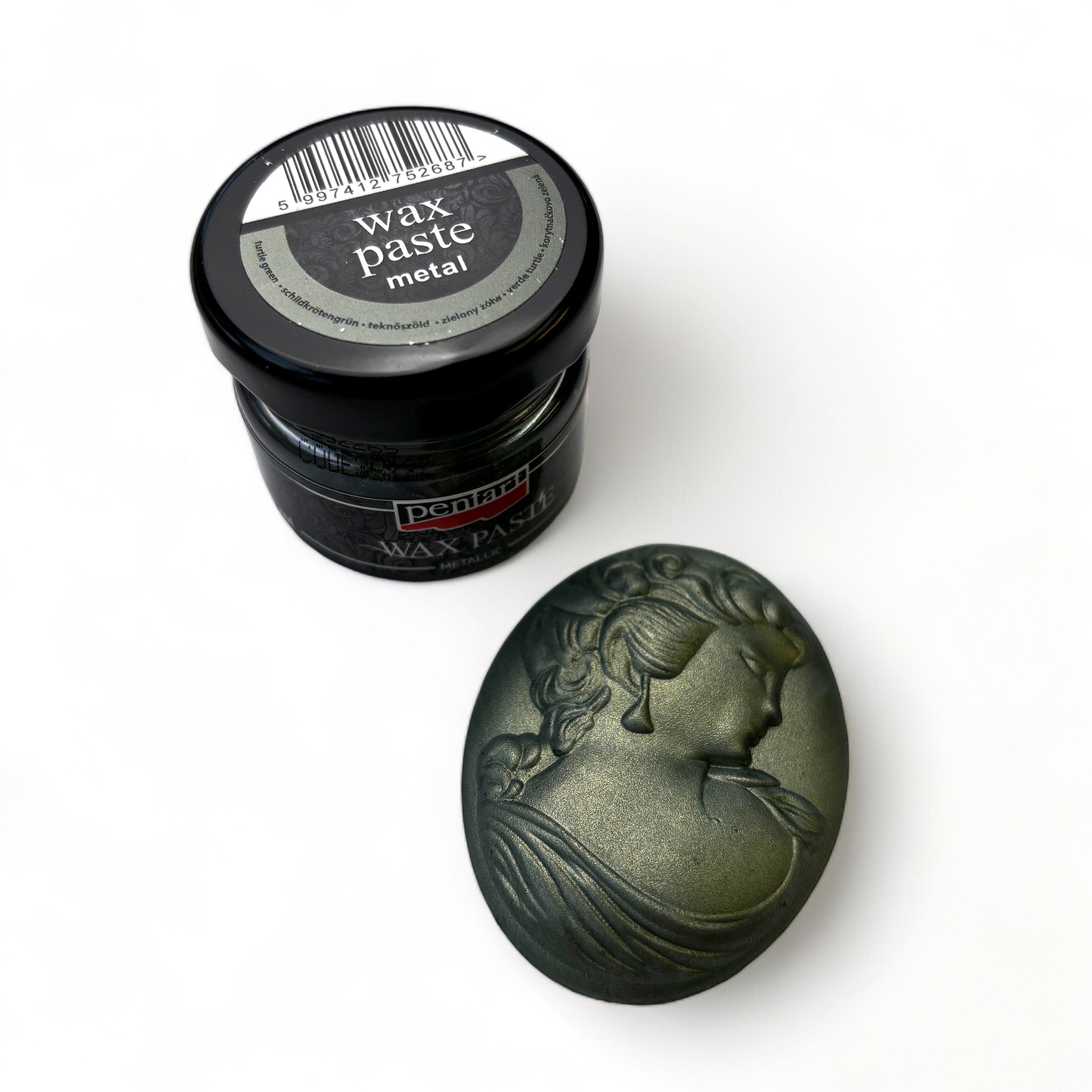 A jar of Pentart's Turtle Green Metallic Wax Paste and a silicone mold casting of a cameo pendant finished in the wax are against a white background.