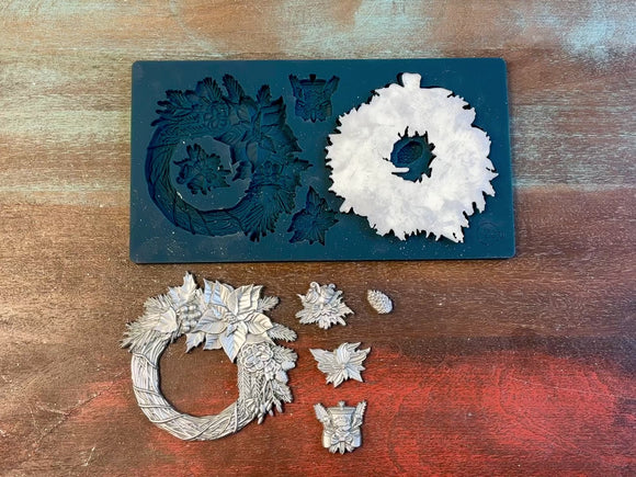 A 14 second video of Zuri Design's Christmas Wreaths is against a wood background. A hand is shown holding one of the wreath castings.