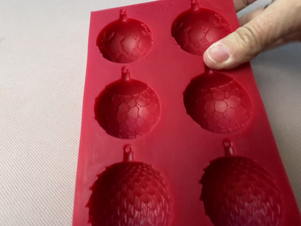 A short 15 second video showcases Get Inspired by Dadarkar Art's Christmas Ornaments red silicone mould. A hand is shown setting down white resin castings of one of each ornament design.
